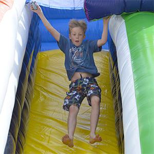 Boy jumping down bouncy castle slide